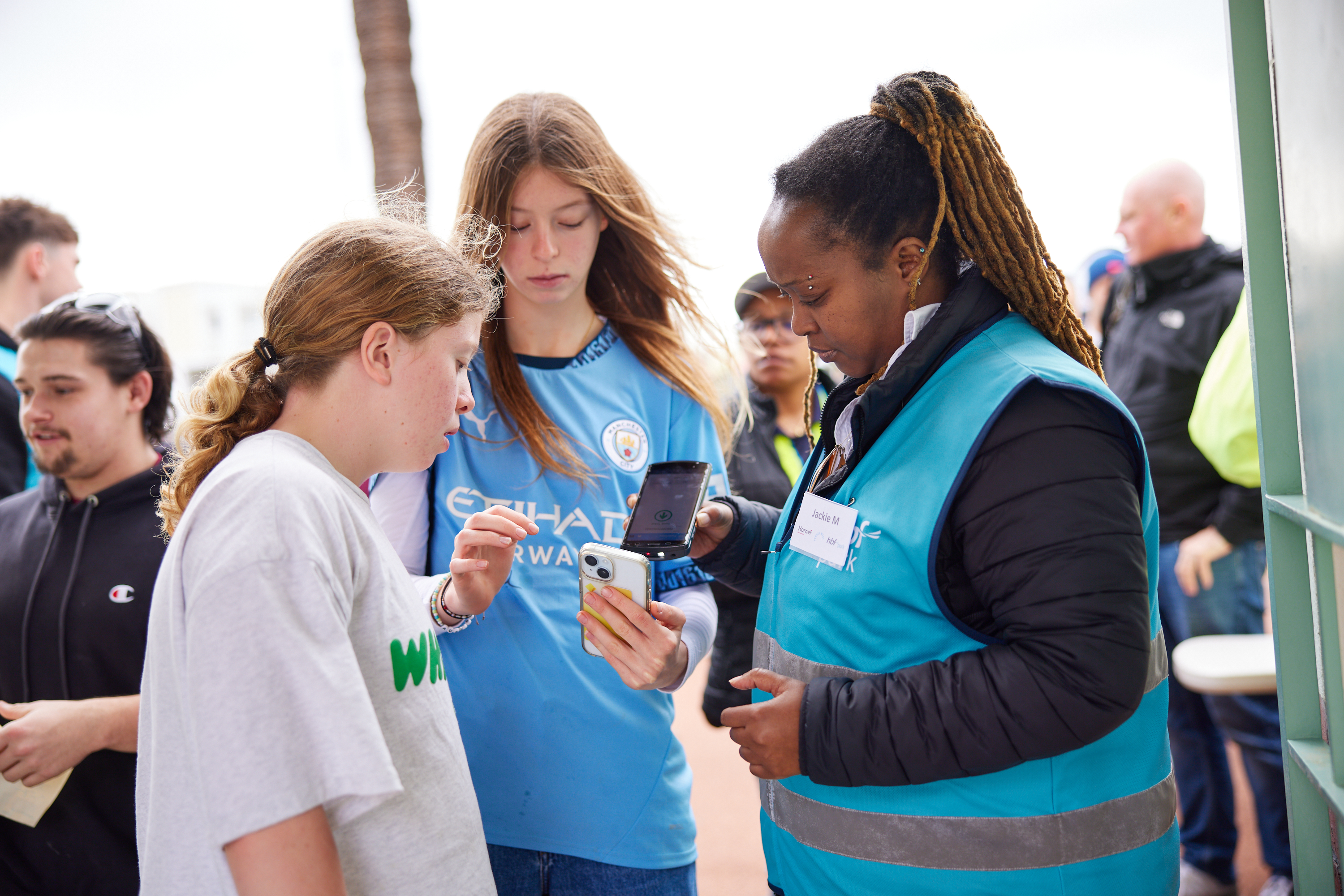 A photo of two girls having their tickets scanned by a ticket attendant