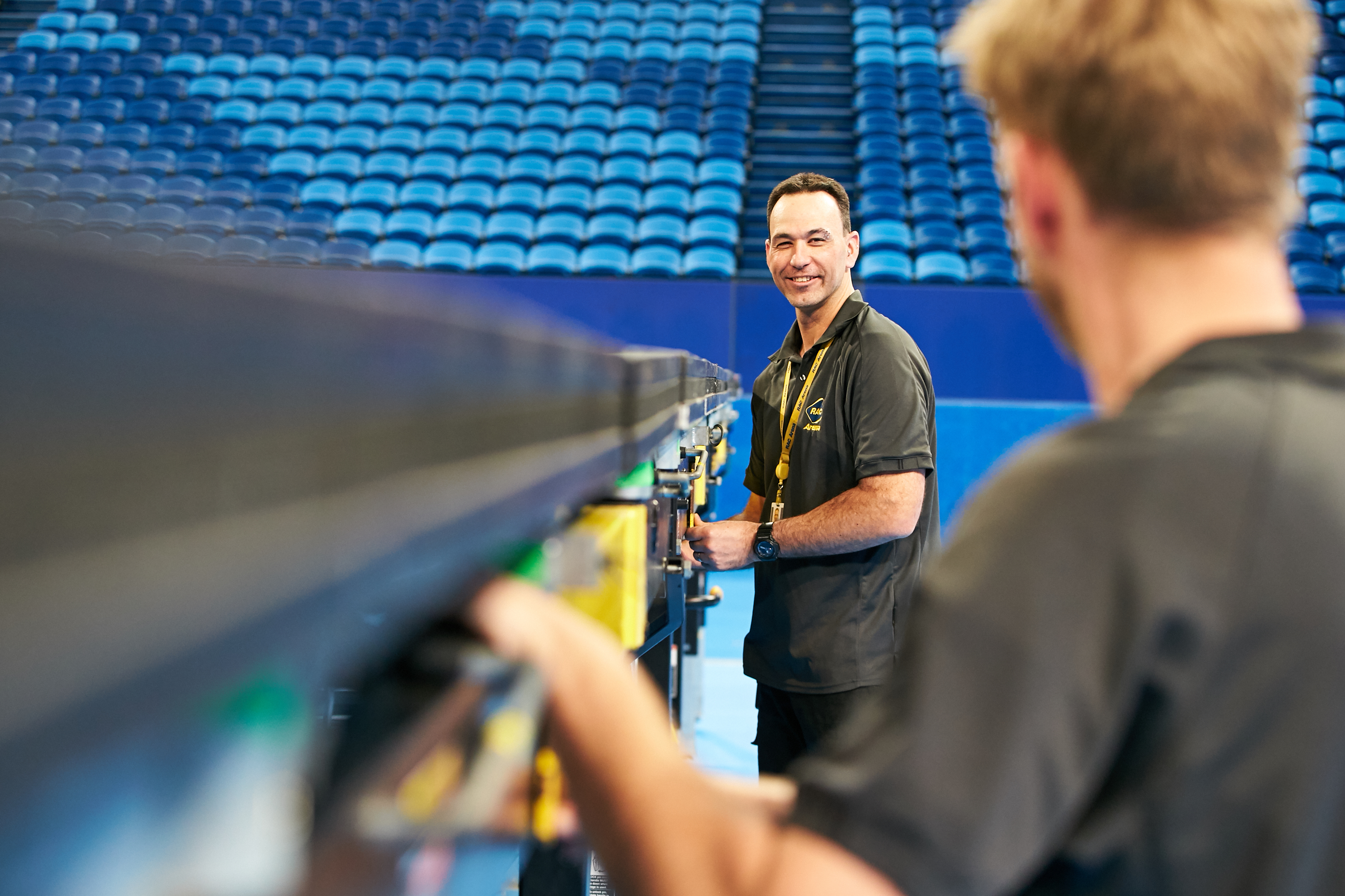 A photo of two men, one in and the other out of focus, tending to tasks inside RAC Arena